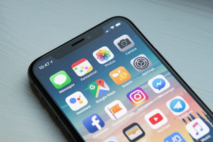 Title: Person holding a smartphone showing a grid of apps - Description: Person holding a smartphone showing a grid of apps