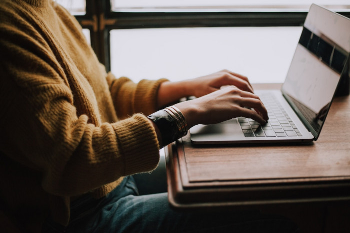 A person typing on a laptop, exploring the concept of cloud faxing.