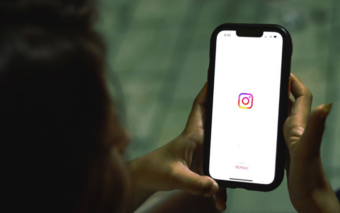 Title: A person holding a smartphone showing a social media app - Description: A person holding a smartphone showing a social media app