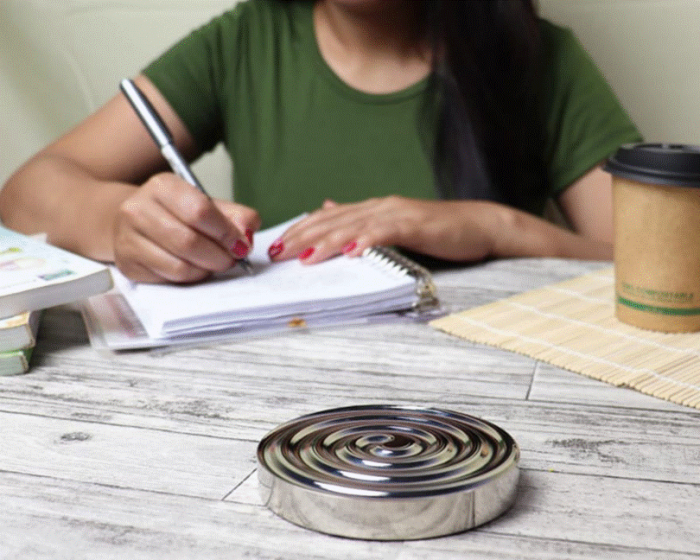 Title: A person writing by hand in a notebook with a coffee nearby - Description: A person writing by hand in a notebook with a coffee nearby