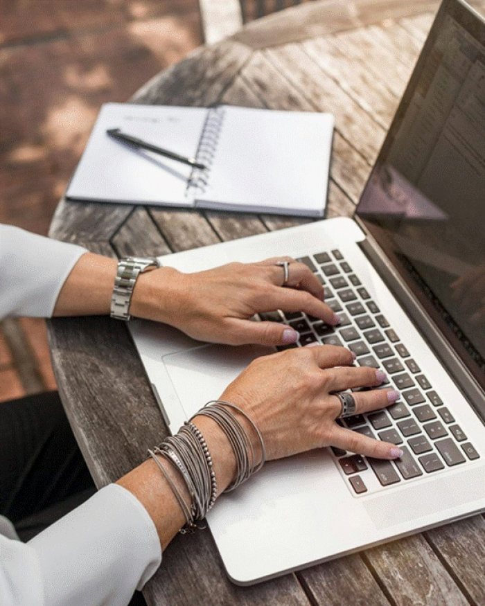 Title: A person typing on a laptop at a wooden table - Description: A person typing on a laptop at a wooden table