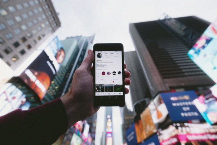 Title: Person browsing the Instagram feed on a phone at a desk - Description: Person browsing the Instagram feed on a phone at a desk