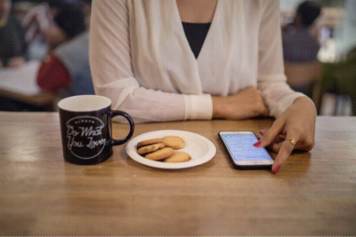 Title: Woman checking her phone by a cafe window - Description: Woman checking her phone by a cafe window