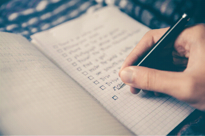 Title: planning - Description: Hand writing a checklist in a notebook