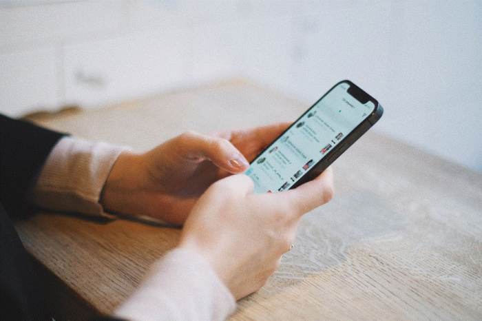 Title: Hands scrolling through social media profiles on a phone - Description: Hands scrolling through social media profiles on a phone